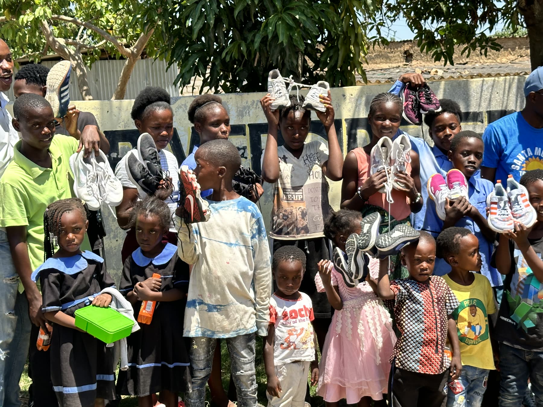 Children in Zambia holding up their new running shoes